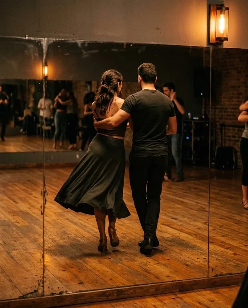 Um par de bachata a dançar lado a lado ao espelho