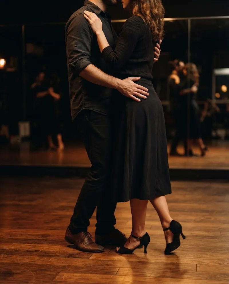 Um par de kizomba em abraço fechado sob luz quente