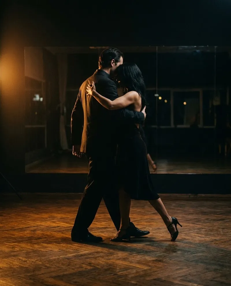 Um par de tango em abraço fechado, luz lateral dramática